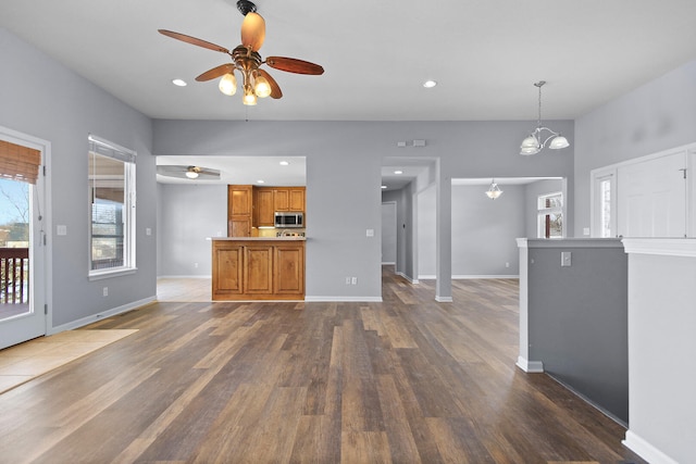 unfurnished living room with dark hardwood / wood-style floors and ceiling fan with notable chandelier