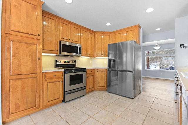 kitchen featuring stainless steel appliances, decorative light fixtures, and light tile patterned floors