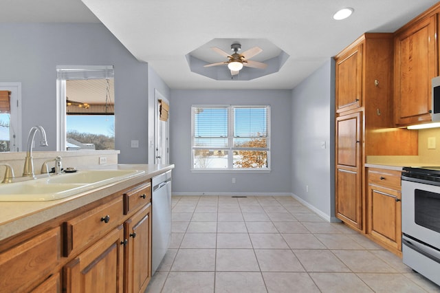 kitchen with stainless steel appliances, sink, a raised ceiling, ceiling fan, and light tile patterned floors