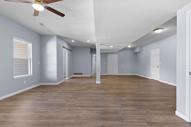 basement featuring ceiling fan, hardwood / wood-style flooring, and a barn door