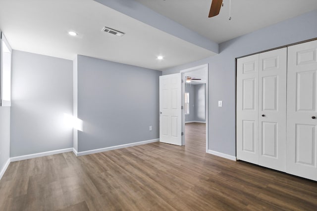 unfurnished bedroom with dark wood-type flooring, ceiling fan, and a closet