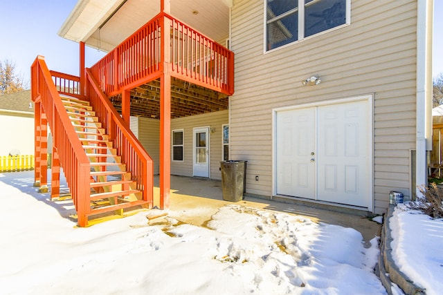 snow covered property entrance with a wooden deck