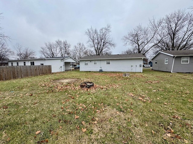 back of property featuring a fire pit, a lawn, and fence