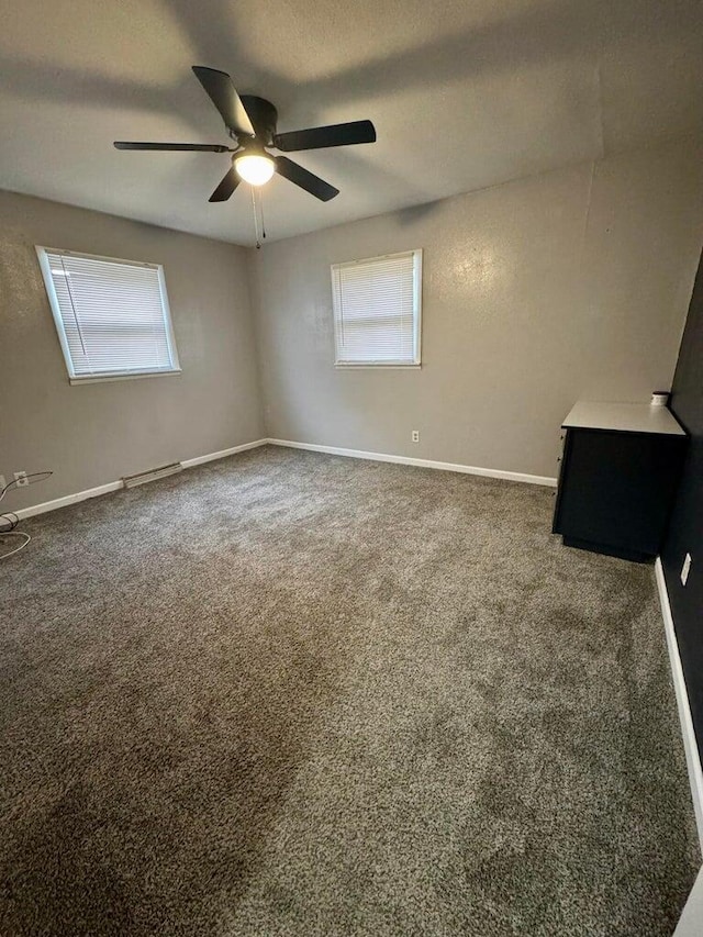 unfurnished room with dark colored carpet, ceiling fan, a textured ceiling, and baseboards