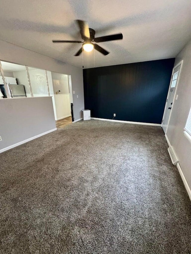 empty room featuring visible vents, baseboards, a ceiling fan, a textured ceiling, and carpet floors