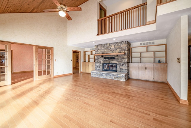 unfurnished living room featuring ceiling fan, a fireplace, light hardwood / wood-style floors, a high ceiling, and wood ceiling