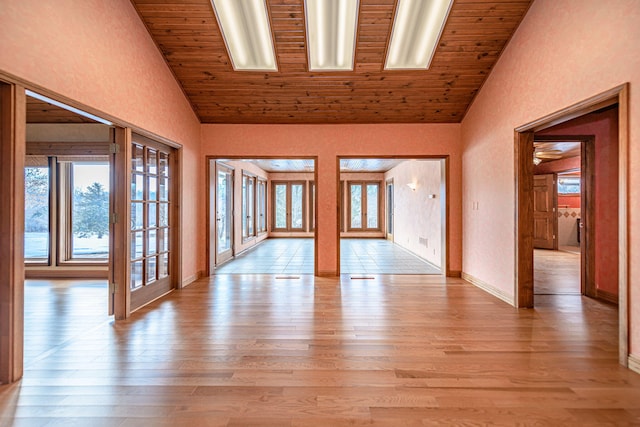 empty room with french doors, wood ceiling, light hardwood / wood-style flooring, and high vaulted ceiling