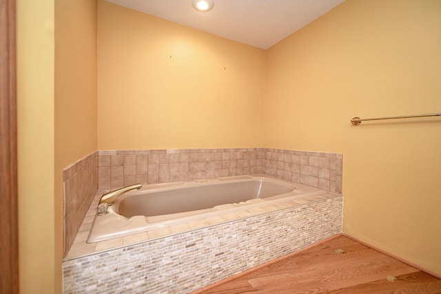 bathroom featuring hardwood / wood-style flooring and a relaxing tiled tub