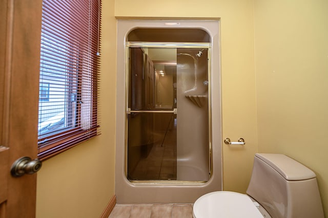 bathroom with toilet, tile patterned flooring, and walk in shower