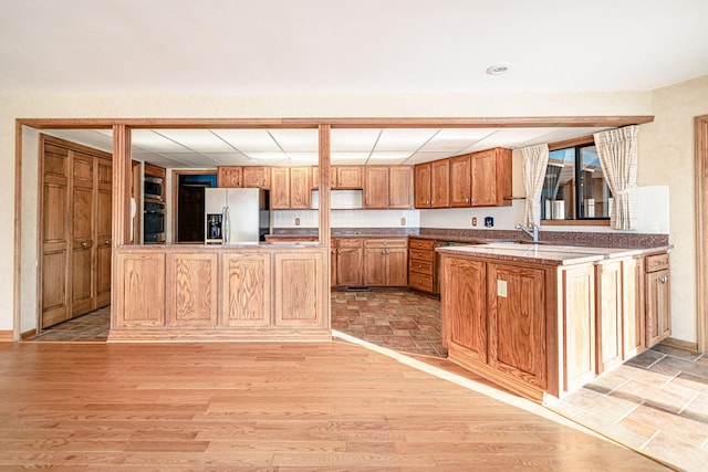 kitchen featuring a center island with sink, light hardwood / wood-style floors, stainless steel fridge, and sink