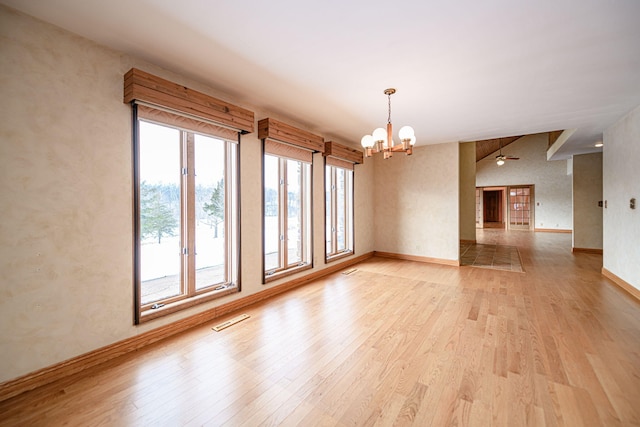 unfurnished room featuring vaulted ceiling, ceiling fan with notable chandelier, and light hardwood / wood-style flooring