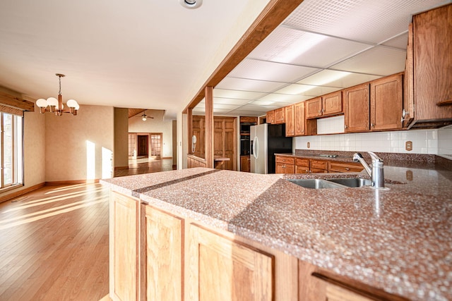 kitchen featuring decorative light fixtures, an inviting chandelier, sink, backsplash, and stainless steel fridge with ice dispenser