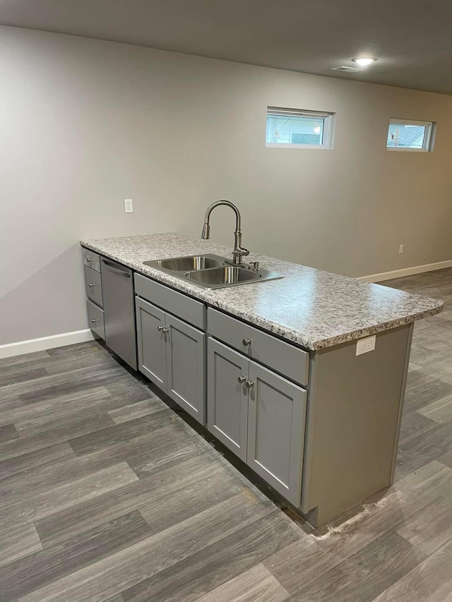 kitchen featuring gray cabinets, stainless steel dishwasher, dark wood-type flooring, and sink