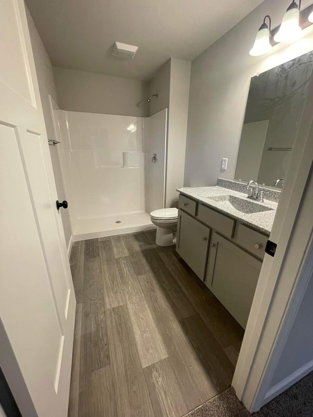 bathroom featuring a shower, vanity, wood-type flooring, and toilet