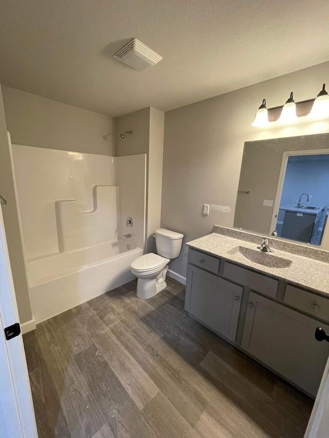 full bathroom with vanity, bathing tub / shower combination, hardwood / wood-style flooring, toilet, and a textured ceiling