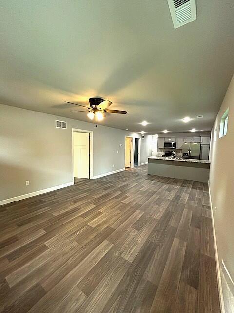 908 7th St, Boonville, MO 65233 - unfurnished living room with dark wood-type flooring, baseboards, and ceiling fan