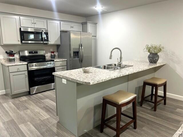 908 7th St, Boonville, MO 65233 - kitchen with stainless steel appliances, a sink, a kitchen breakfast bar, gray cabinets, and a peninsula