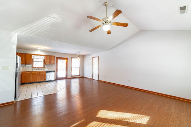 unfurnished living room featuring sink, ceiling fan, light hardwood / wood-style flooring, and lofted ceiling