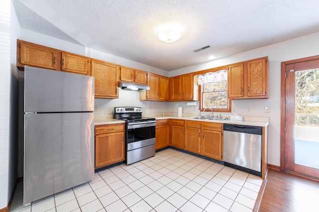 kitchen featuring appliances with stainless steel finishes, a textured ceiling, sink, and light tile patterned floors