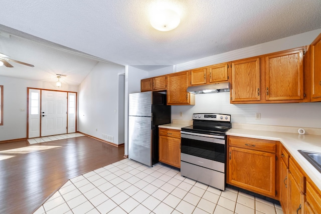 kitchen with stainless steel appliances, sink, a textured ceiling, lofted ceiling, and ceiling fan