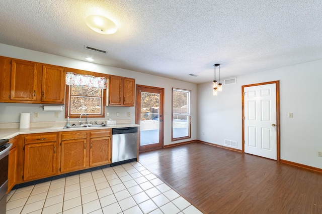 kitchen featuring a textured ceiling, decorative light fixtures, stainless steel appliances, light wood-type flooring, and sink