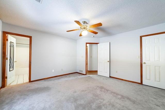 unfurnished bedroom with ensuite bath, light carpet, ceiling fan, and a textured ceiling