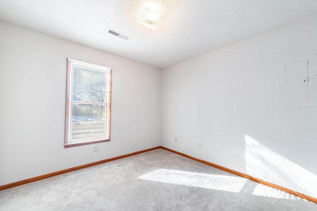 carpeted spare room featuring electric panel and a textured ceiling