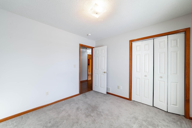 unfurnished bedroom featuring a closet, light carpet, and a textured ceiling