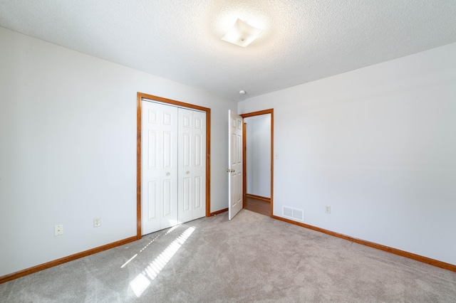 unfurnished bedroom with a textured ceiling, a closet, and light carpet