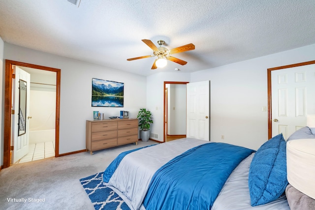 carpeted bedroom featuring ensuite bathroom, a textured ceiling, and ceiling fan