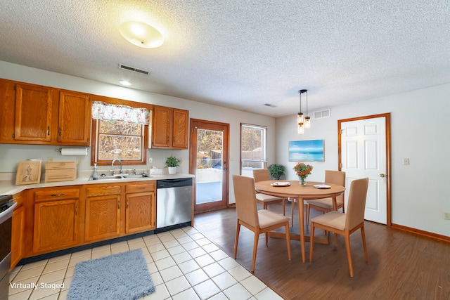 kitchen featuring sink, a textured ceiling, light tile patterned floors, pendant lighting, and appliances with stainless steel finishes