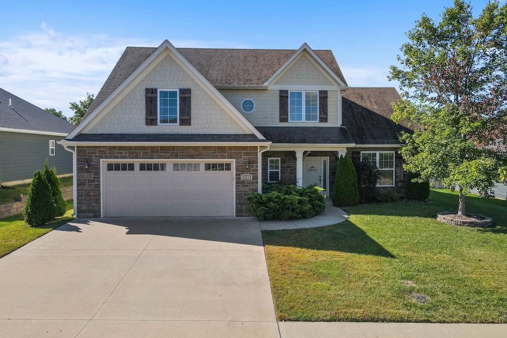 craftsman inspired home featuring a garage and a front lawn