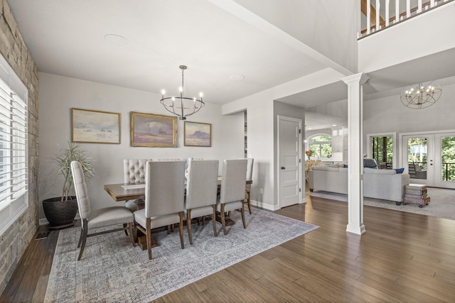 dining room with a notable chandelier, dark hardwood / wood-style floors, french doors, and decorative columns