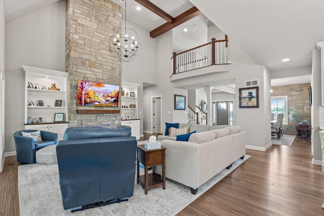 living room featuring beam ceiling, ornate columns, an inviting chandelier, a towering ceiling, and hardwood / wood-style flooring