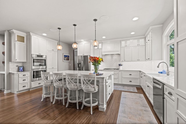 kitchen with sink, hanging light fixtures, a kitchen island, white cabinets, and appliances with stainless steel finishes