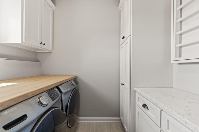 laundry room with light hardwood / wood-style floors, cabinets, and washing machine and clothes dryer