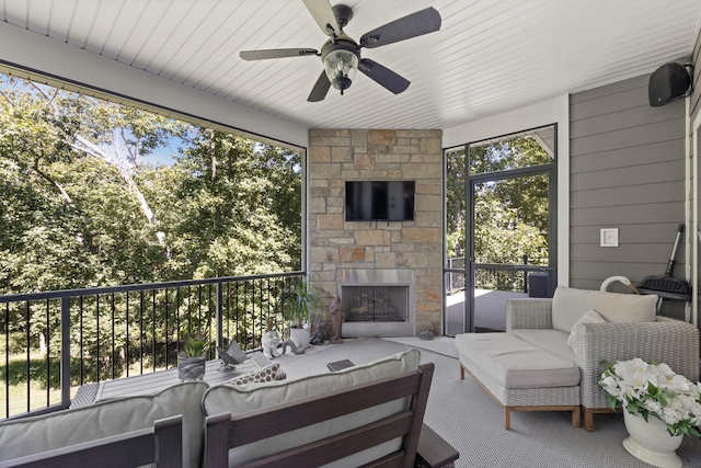 sunroom with ceiling fan and an outdoor stone fireplace