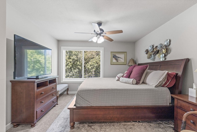 bedroom with a textured ceiling, ceiling fan, and light carpet