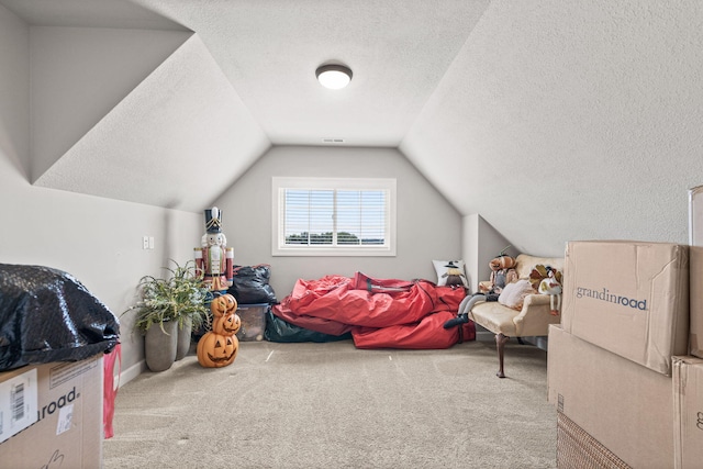 recreation room featuring carpet, a textured ceiling, and vaulted ceiling