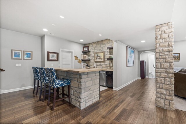 kitchen featuring kitchen peninsula, dishwasher, a breakfast bar, and dark hardwood / wood-style floors