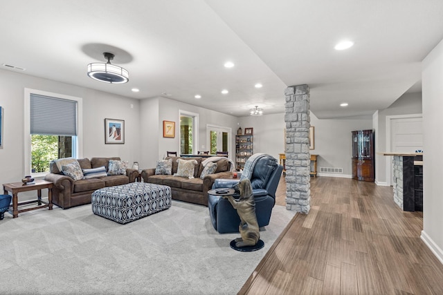 living room featuring bar area, wood-type flooring, and ornate columns