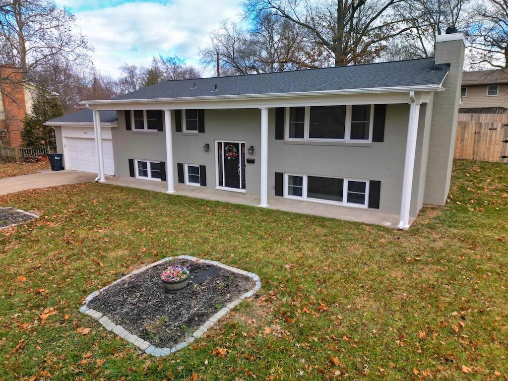 exterior space with an attached garage, fence, concrete driveway, a lawn, and a chimney