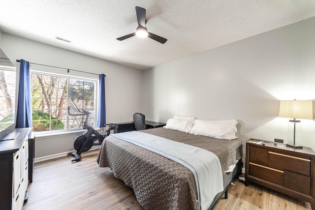 bedroom featuring light wood-type flooring, ceiling fan, and a textured ceiling