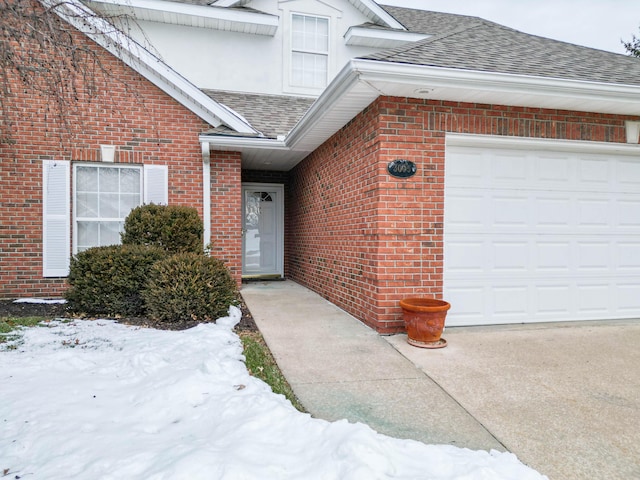 snow covered property entrance featuring a garage