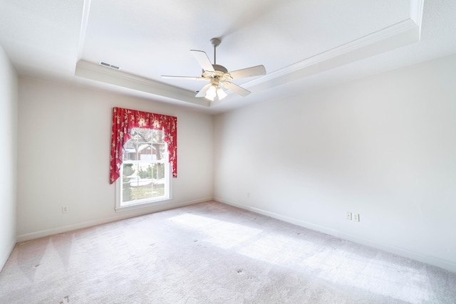 carpeted spare room with ceiling fan, crown molding, and a raised ceiling