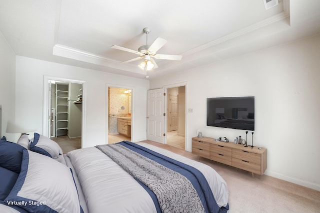 bedroom featuring ceiling fan, light colored carpet, a tray ceiling, a spacious closet, and a closet