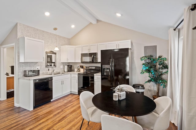 kitchen with pendant lighting, sink, white cabinetry, light hardwood / wood-style floors, and black appliances