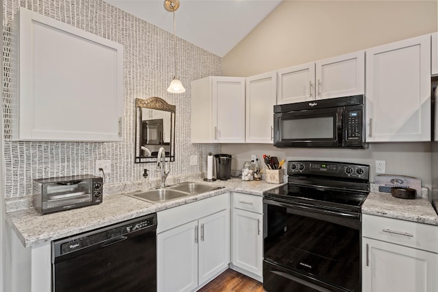 kitchen featuring white cabinets, black appliances, sink, hanging light fixtures, and vaulted ceiling