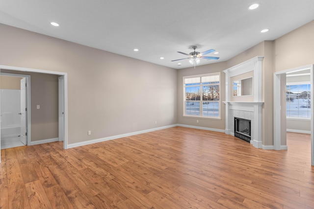 unfurnished living room with ceiling fan, light hardwood / wood-style flooring, and a tile fireplace