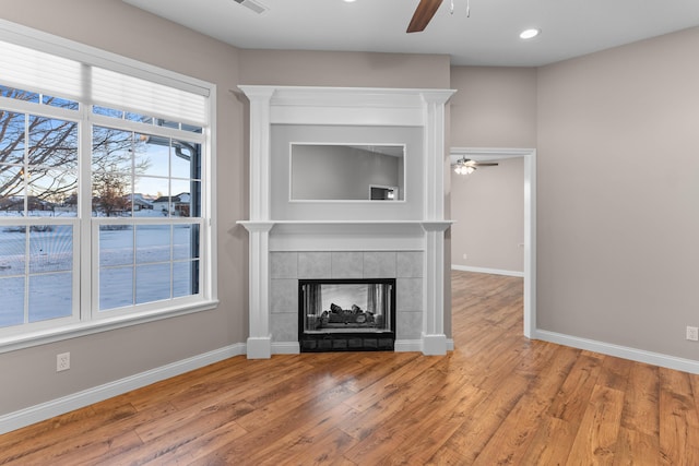 unfurnished living room featuring hardwood / wood-style floors, a fireplace, ceiling fan, and a healthy amount of sunlight